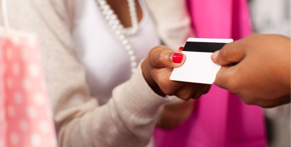 Woman using a plastic reward card in a store for savings on her purchase.