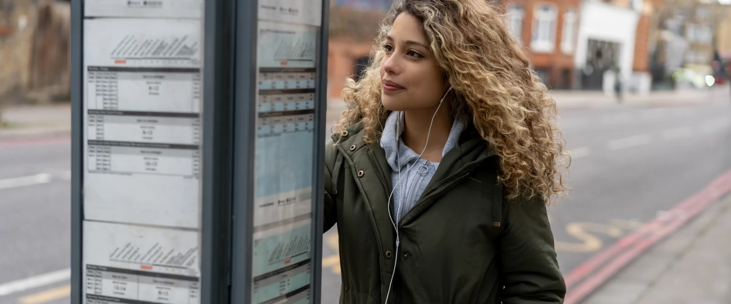 Woman checking the bus timetable at a London bus stop